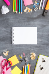 School supplies on a blackboard background. Notebook in the center. Concept back to school. With copy spice. Top view. Vertical layout