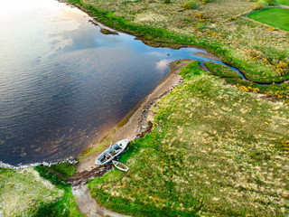 Old boat left on a small beach along the Ring of Kerry route. Rugged coast of on Iveragh Peninsula on sunset, County Kerry, Ireland.