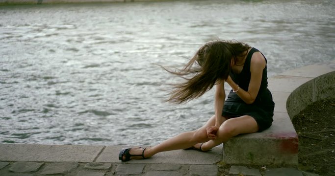 girl with long legs sits on parapet at river slow motion