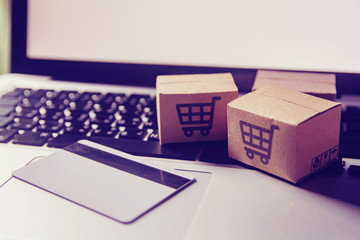 Online shopping - Paper cartons or parcel with a shopping cart logo and credit card on a laptop keyboard. Shopping service on The online web and offers home delivery.