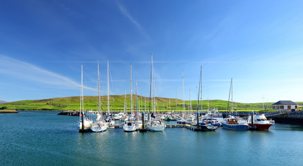 Colorful fishing boats and yachts at the harbor of Dingle town on the West Atlantic coast of Ireland. Towns and villages on famous Dingle Peninsula tourist route.