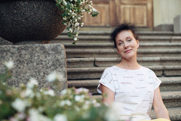 Fototapeta premium A beautiful tourist of Mature age sits on the steps in the city of St. Petersburg