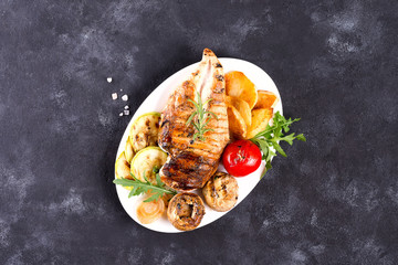 Grilled chicken breast on a plate with tomatoes, mushrooms on a stone background, flat lay