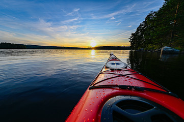 red plastic kayak on calm water in the sunset