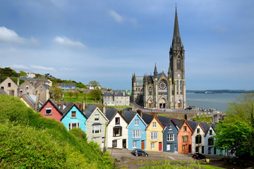 Fototapeta na wymiar Colorful row houses with St. Colman's Cathedral in background in the port town of Cobh, County Cork, Ireland