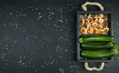 Fresh zucchini, mushrooms on a black board. View from above. Copy space