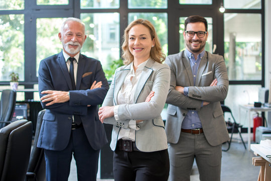 Three Business People Standing With Their Arms Crossed In Office