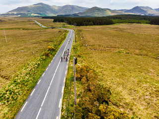 Professional cyclists competing in Connemara region in Ireland. Scenic Irish countryside landscape with mountains on the horizon, County Galway, Ireland.