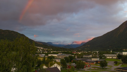 Fototapeta na wymiar Night sky with rainbow in Orsta Norway. Panoramic aerial view from drone at sunset in july 2019
