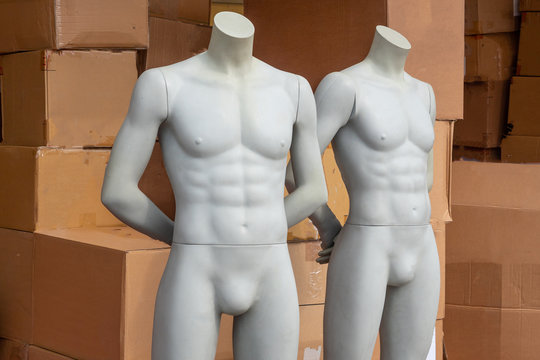 Mannequins of men on the background of cardboard boxes with clothes.