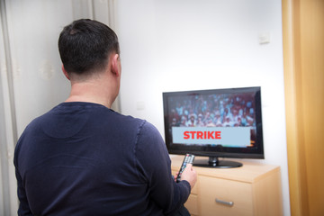 A passive man watching television news about a political strike,