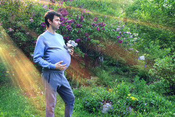 The concept of male pregnancy. Funny young father with stuffed toy in hand
