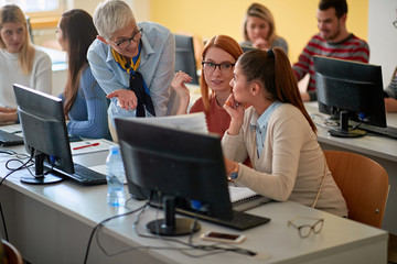 lecturer with girl students working in computer class on university campus.