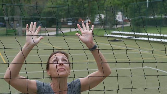 Games in volleydoll. A woman with her hands raised with a volleyball net.