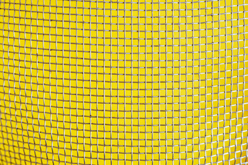 Dirty metal net on a yellow background. Rusty worn cells