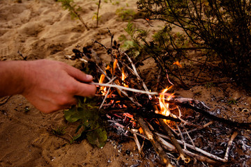 man makes a fire from branches in the forest