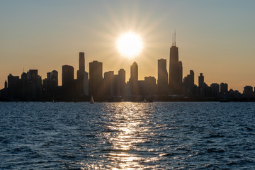 Obraz premium Chicago skyline sunset silhouette with sun reflecting off water in foreground (landscape)