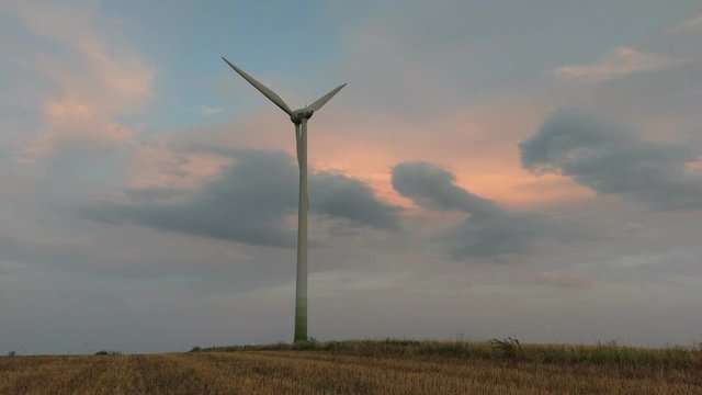 Wind turbines for green energy generation in fast motion time-lapse at dusk in Burgenland plains.