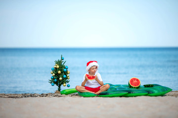 A boy eats a watermelon on the beach in the New Year.