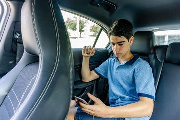 Young teenager with mobile sitting in luxury limousine.