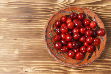 Red sweet cherry in a clay plate on a wooden table