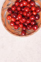 Red sweet cherry in a clay plate on a cream table