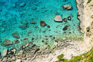 Above view of clear blue sea with rocky beach