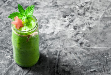 Tropical cocktail. Smoothie with mint, slices of watermelon and ice cubes on a gray concrete surface. View from above. Copy space
