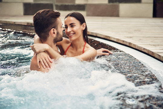 Smiling woman in red swimsuit loving hugging bearded boyfriend