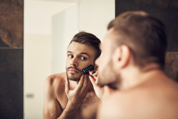 Man shaving careful beard in the bathroom