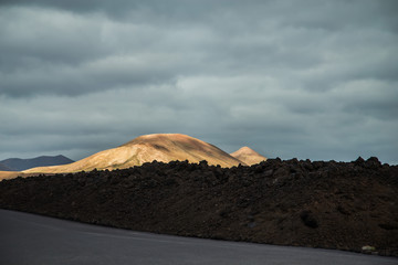 Fototapeta na wymiar incredibly beautiful volcanoc landscape with black sand and red mountains and a beautiful sky during the day on the spanish island of Canary Lanzarote