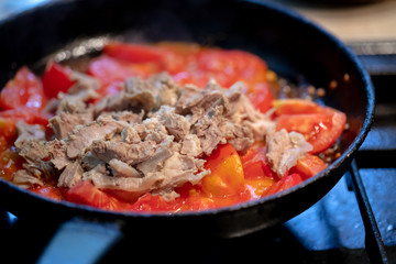 bachelor man cooking snake with boiled meat and tomatoes at pan. domestic bachelors meals eating.