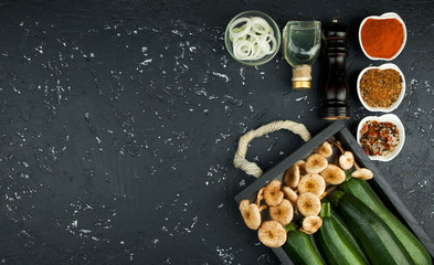 Fresh zucchini, mushrooms, spices and herbs on a black board. View from above. Copy space