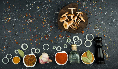 Fresh mushrooms with spices and herbs on black board. View from above. Copy space.
