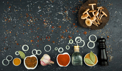 Fresh mushrooms with spices and herbs on black board. View from above. Copy space.