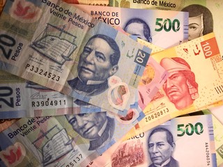 Mexican peso bills spread randomly over a flat surface