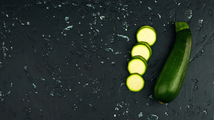 Fresh green zucchini on a dark table. The view from the top. Copy space.