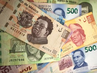 Mexican peso bills spread randomly over a flat surface