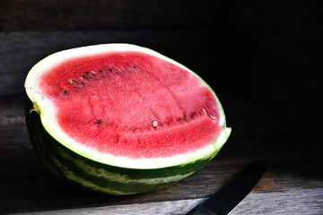 A watermelon cut in half, on an old rustic table.
