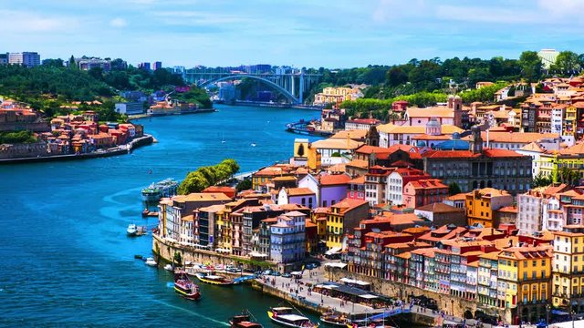 Porto, Portugal. Aerial view of Ribeira area in Porto, Portugal during a sunny day with river, colorful buildings and bridge. Time-lapse dugin the day, zoom in