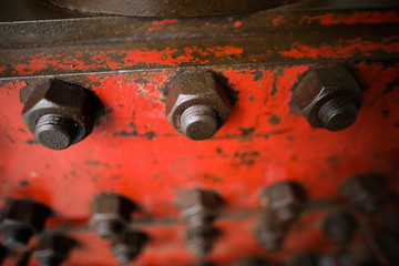 Shallow depth of field image with worn out heavy iron industrial equipment used in the oil and gas drilling industry (rusty bolts, nuts, pipes, levers)