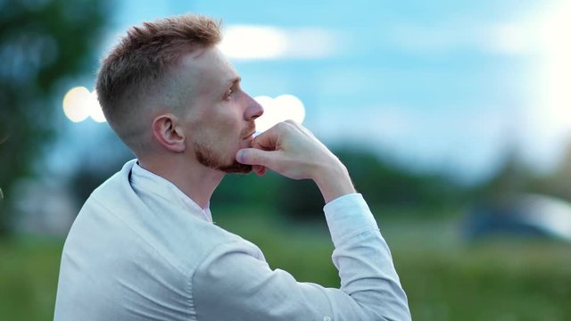 Pensive bearded European guy thinking and relaxing at evening outdoor medium close-up