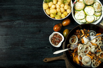 Vegetables on the background. Fried zucchini sauce in a plate. Young boiled potatoes with dill in a bowl. Fried chanterelle mushrooms with golden onions in a frying pan. copy space
