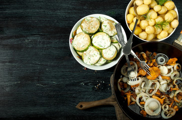 Vegetables on the background. Fried zucchini sauce in a plate. Young boiled potatoes with dill in a bowl. Fried chanterelle mushrooms with golden onions in a frying pan. copy space