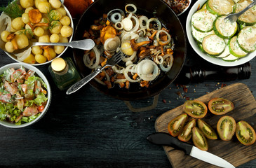 Vegetables on the background. Fried zucchini sauce in a plate. Young boiled potatoes with dill in a bowl. Fried chanterelle mushrooms with golden onions in a frying pan. copy space