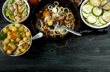 Vegetables on the background. Fried zucchini sauce in a plate. Young boiled potatoes with dill in a bowl. Fried chanterelle mushrooms with golden onions in a frying pan. copy space