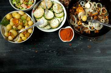 Vegetables on the background. Fried zucchini sauce in a plate. Young boiled potatoes with dill in a bowl. Fried chanterelle mushrooms with golden onions in a frying pan. copy space