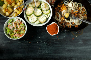 Vegetables on the background. Fried zucchini sauce in a plate. Young boiled potatoes with dill in a bowl. Fried chanterelle mushrooms with golden onions in a frying pan. copy space