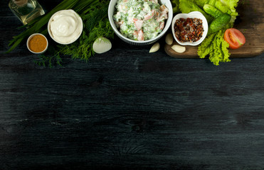 Salad with vegetables. View from above. Fresh salad in a plate on a dark background. Garlic, tomato, cucumber, dill and onion in a dish of dark surface. Copy space.