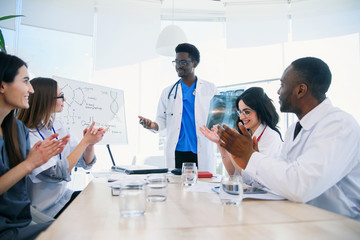 International group of professional young doctors are clapping their hands and smiling at a medical...